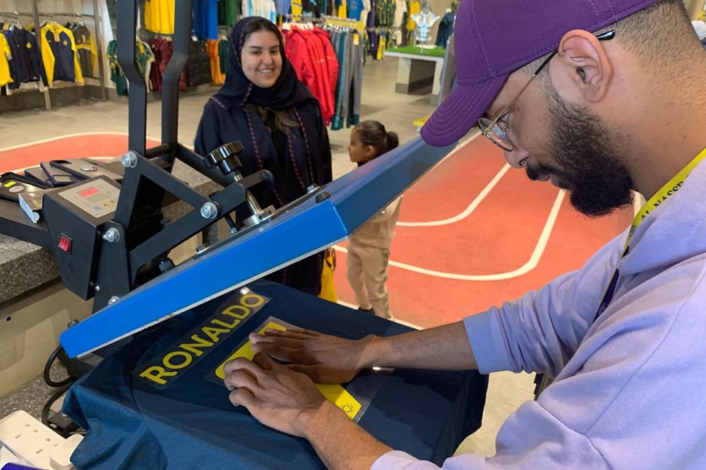 عامل في متجر النصر يجهز قميص رونالدو