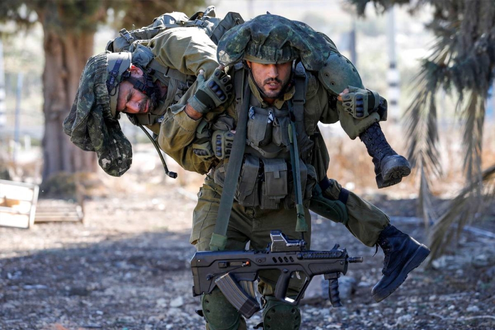 جندي إسرائيلي يحمل آخر خلال تدريبات قرب الحدود اللبنانية أمس (أ ف ب)