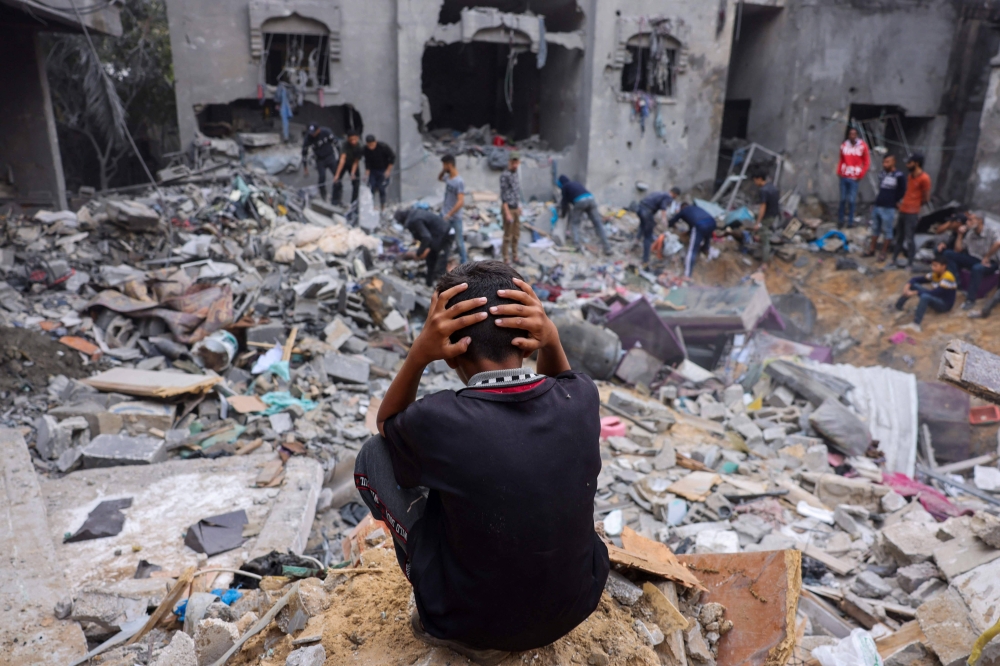 طفل فلسطيني أمام أنقاض منزله المدمر جراء القصف