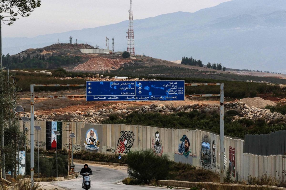 لبناني يمر أمام جدار حدودي قرب موقع عسكري إسرائيلي في بلدة العديسة (أ ف ب)