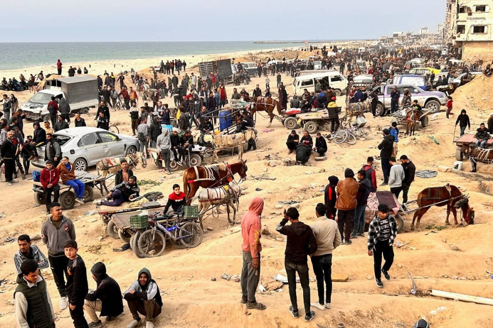 فلسطينيون ينتظرون المساعدات في غزة (رويترز)