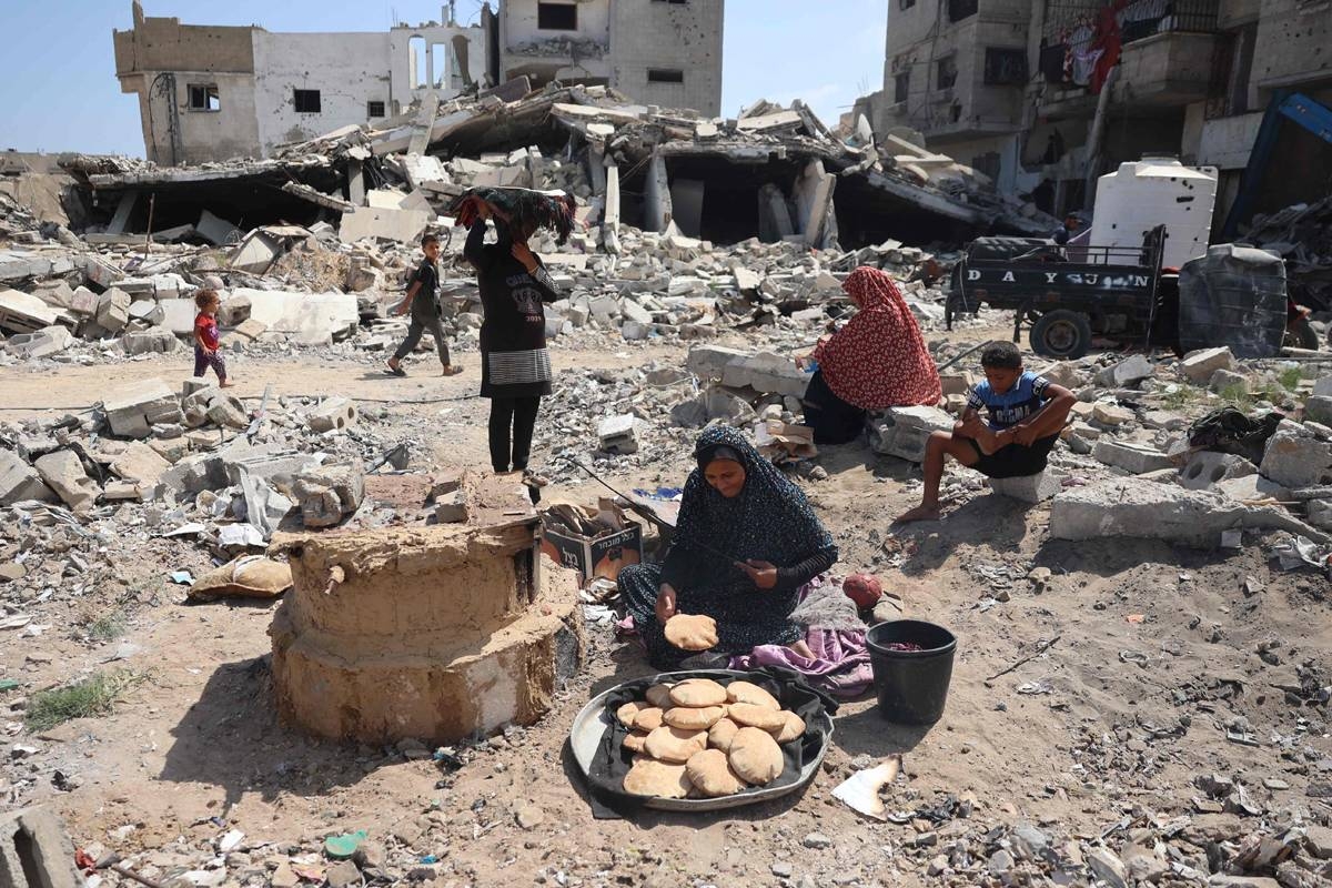 فلسطينية تعد الخبز بالقرب من منازل مدمرة في خان يونس جنوب غزة أمس (أ ف ب)