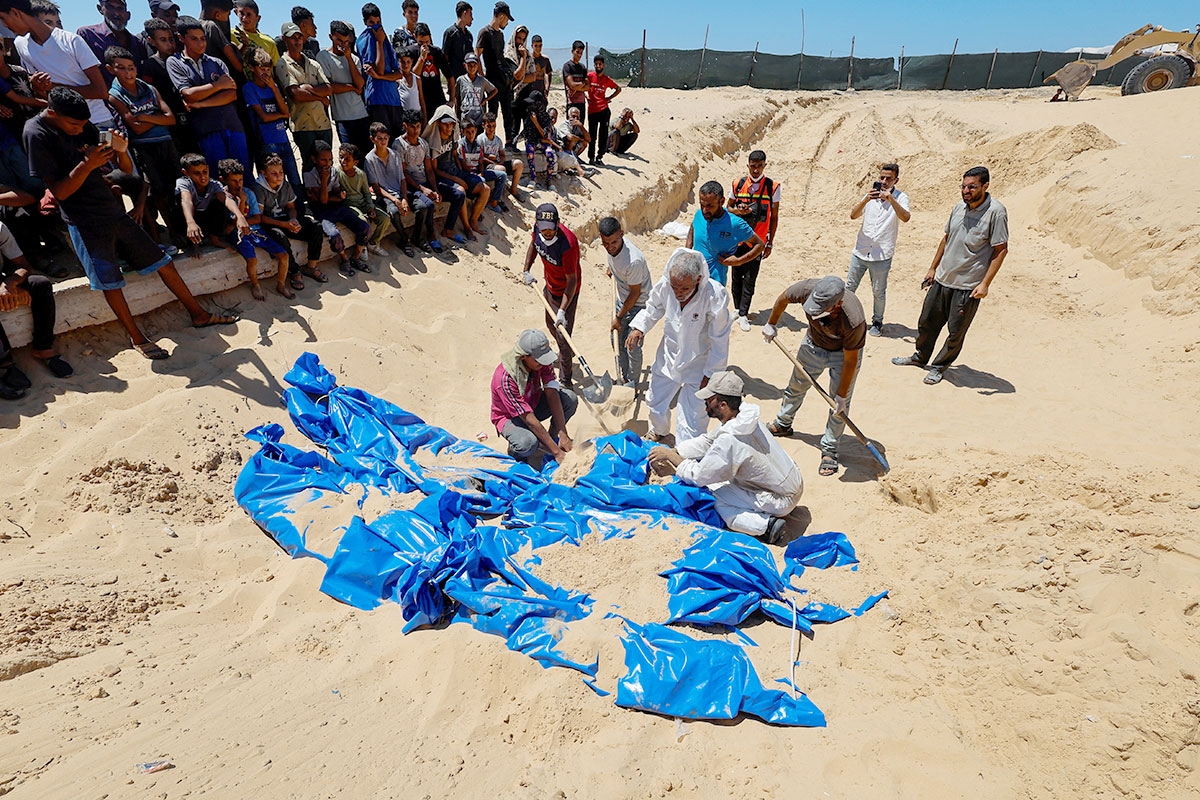 فلسطينيون يعيدون دفن جثامين سلمتها سلطات الاحتلال بعد نبشها مقبرة في خان يونس جنوب غزة أمس (رويترز)